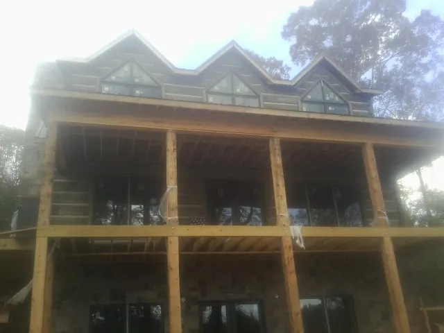 Dormers and porch framing on a large log home under construction — Roof Coating work by our crew in Alta Vista