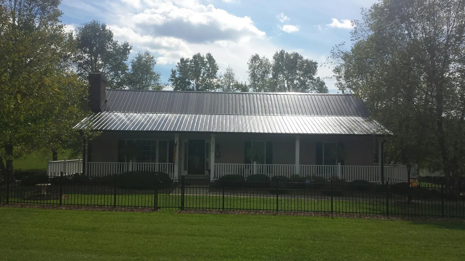 Gray metal roof on a brick ranch with a full width front porch — Gutter Guard Installation work by our crew in Alta Vista