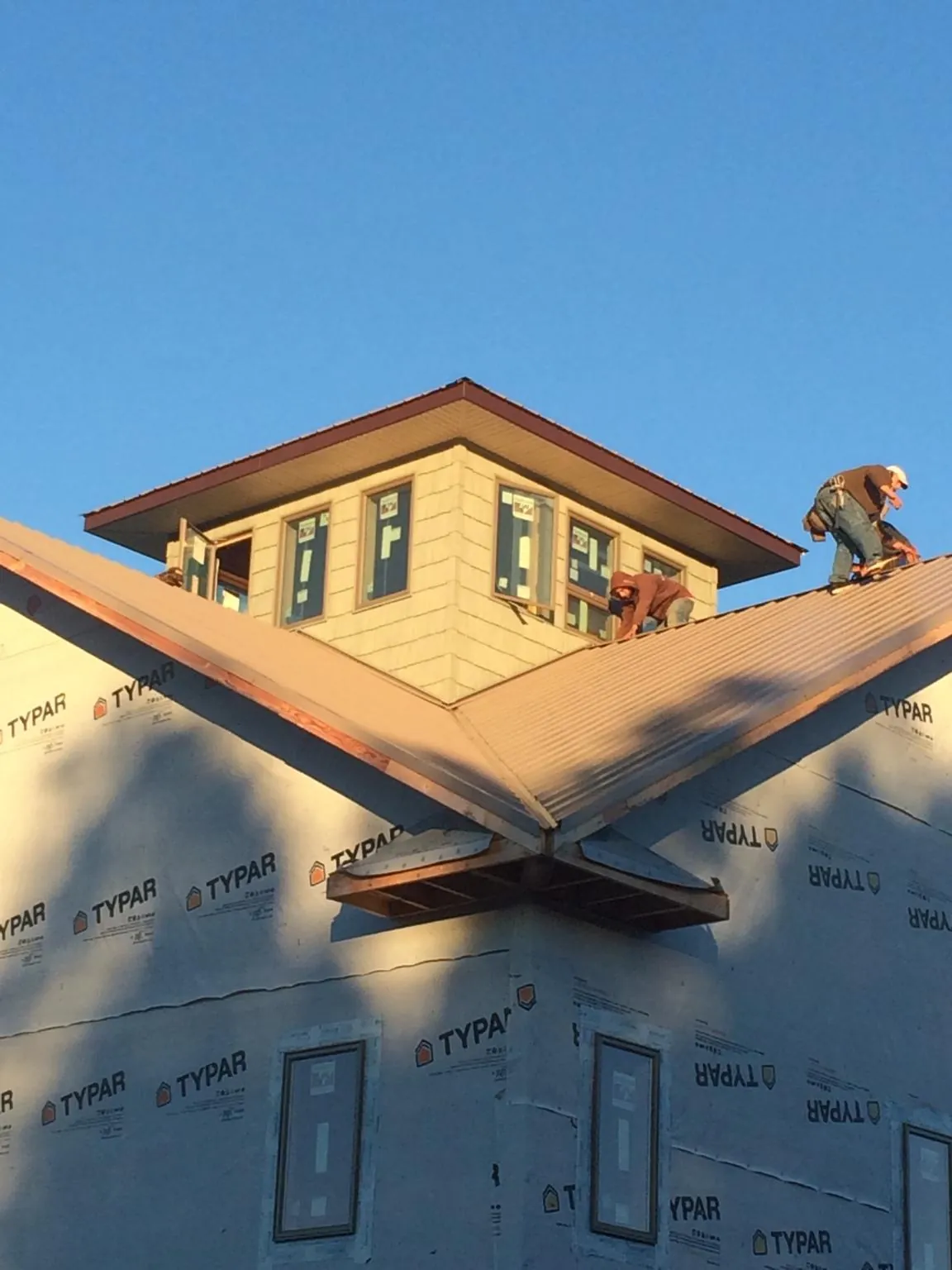 Roofers working around a rooftop cupola on a new metal roof at sunset — Roof Waterproofing in Alta Vista by Roofing Brothers